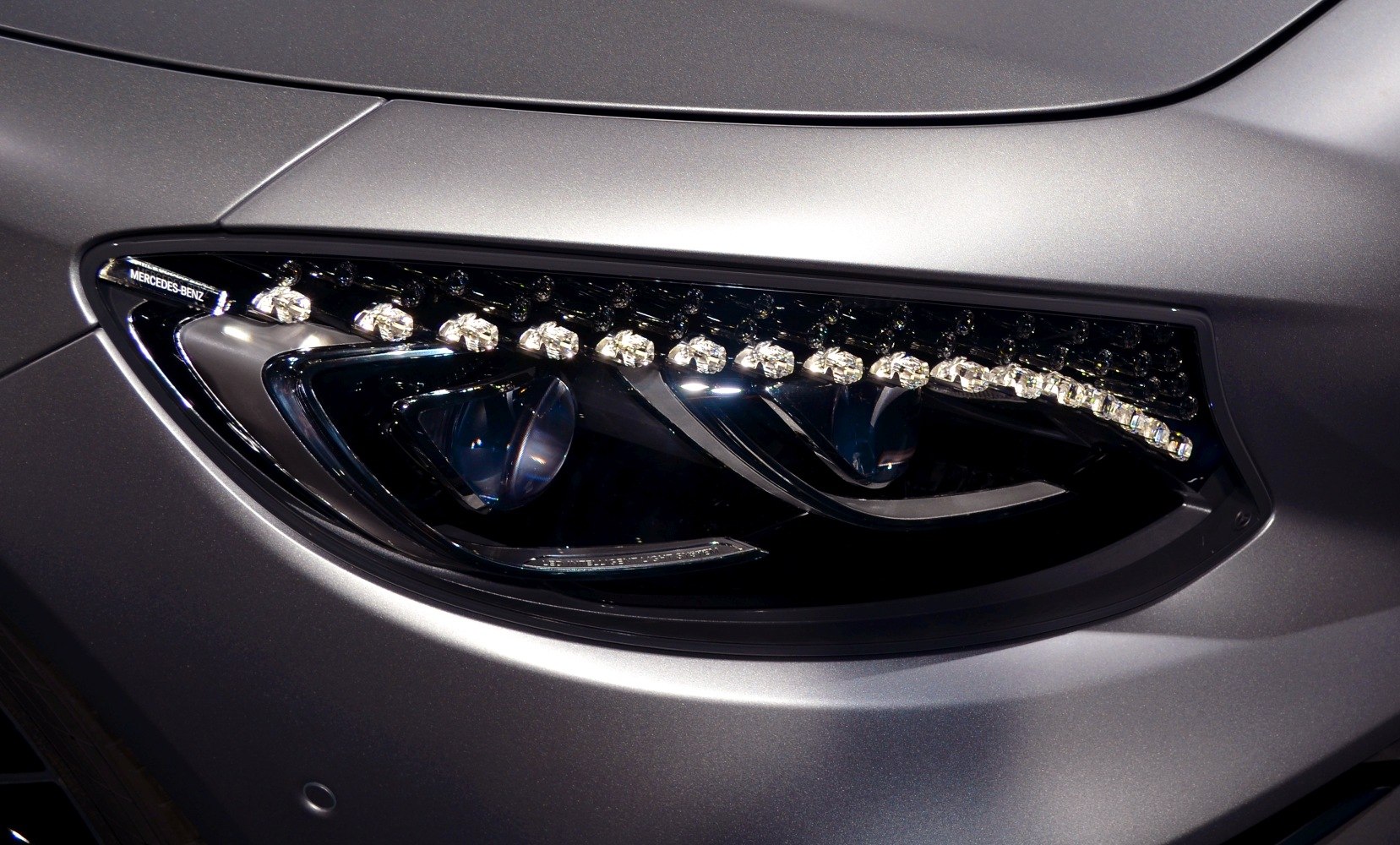 Close-up of advanced LED headlight with sleek design and MERCEDES-BENZ branding.