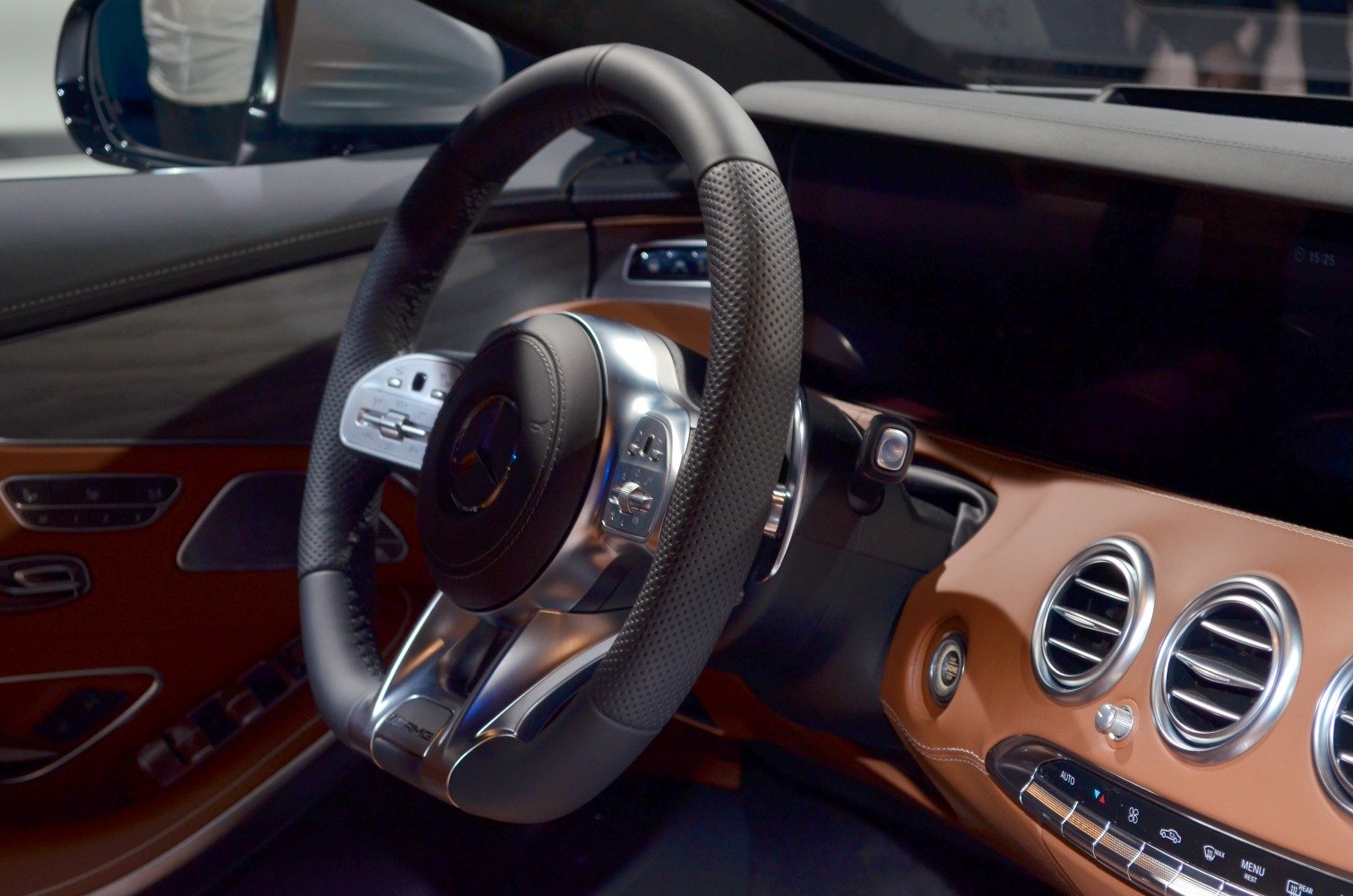 Luxury steering wheel with multifunction controls and premium brown leather dashboard.