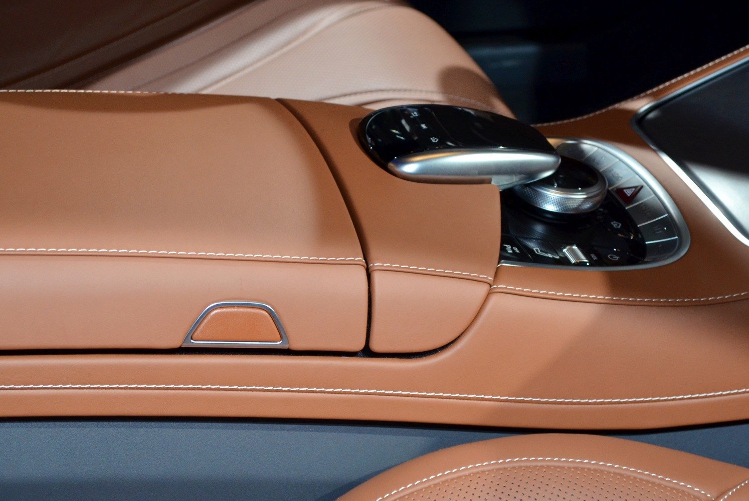 Luxury brown leather center console with stitched detail and touchpad control