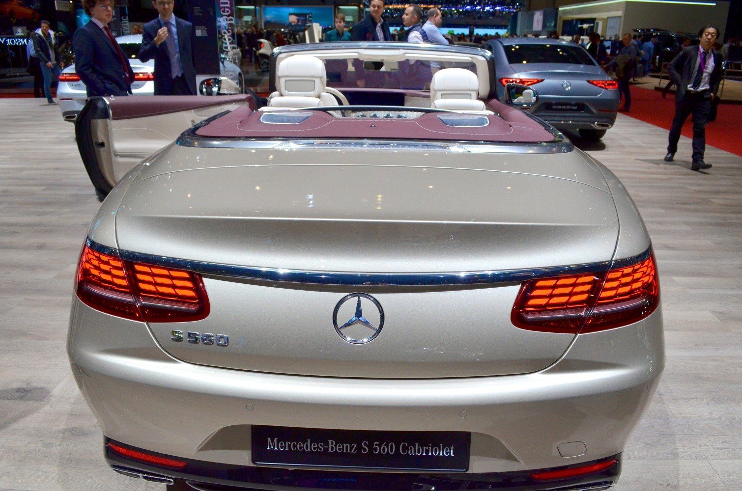 Rear view of convertible with illuminated taillights and white leather seats.