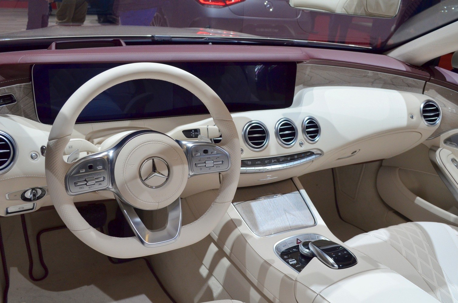 Modern luxury steering wheel and dashboard with beige leather and wood trim