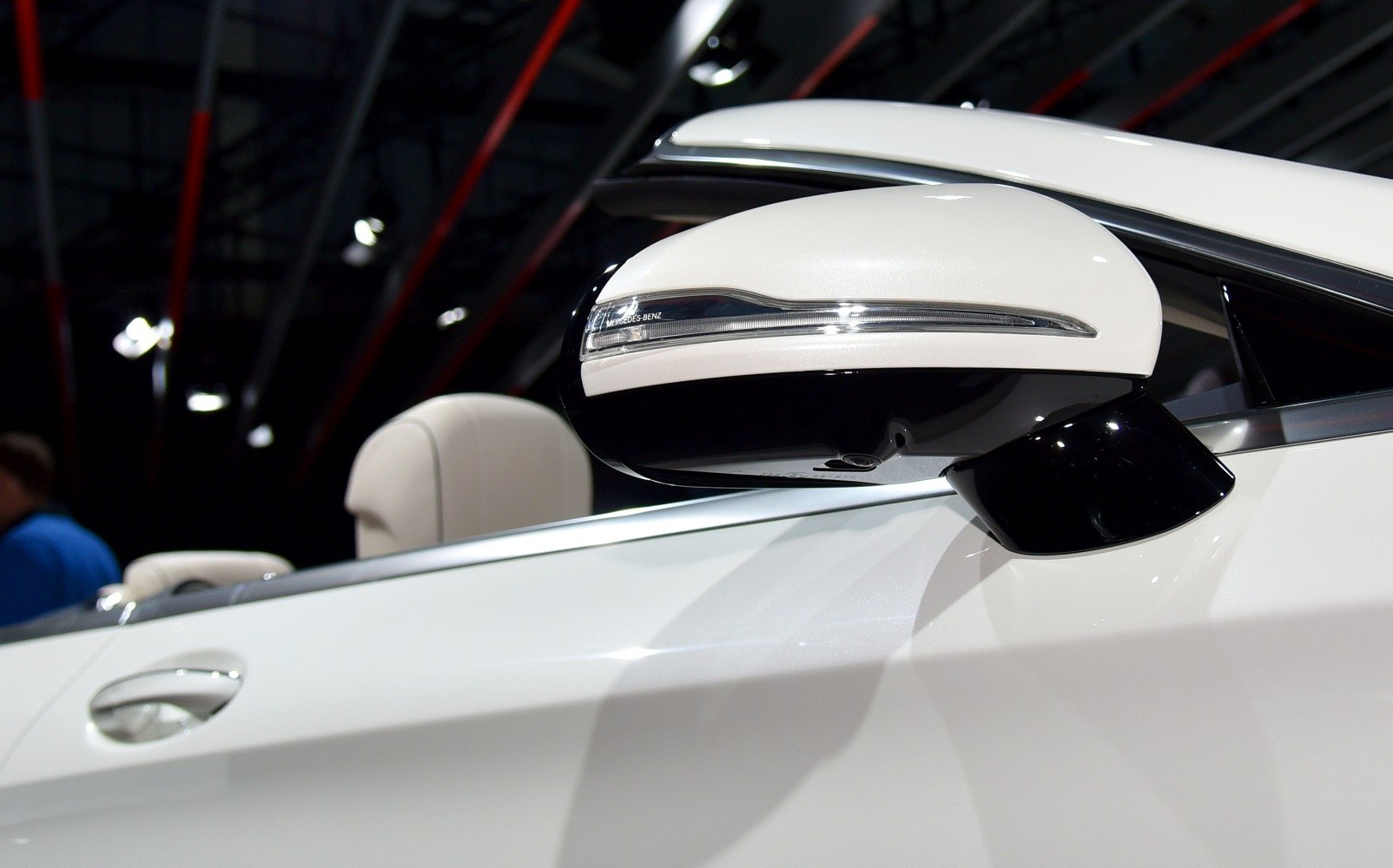 Close-up of a luxury car's side mirror and door handle in white.