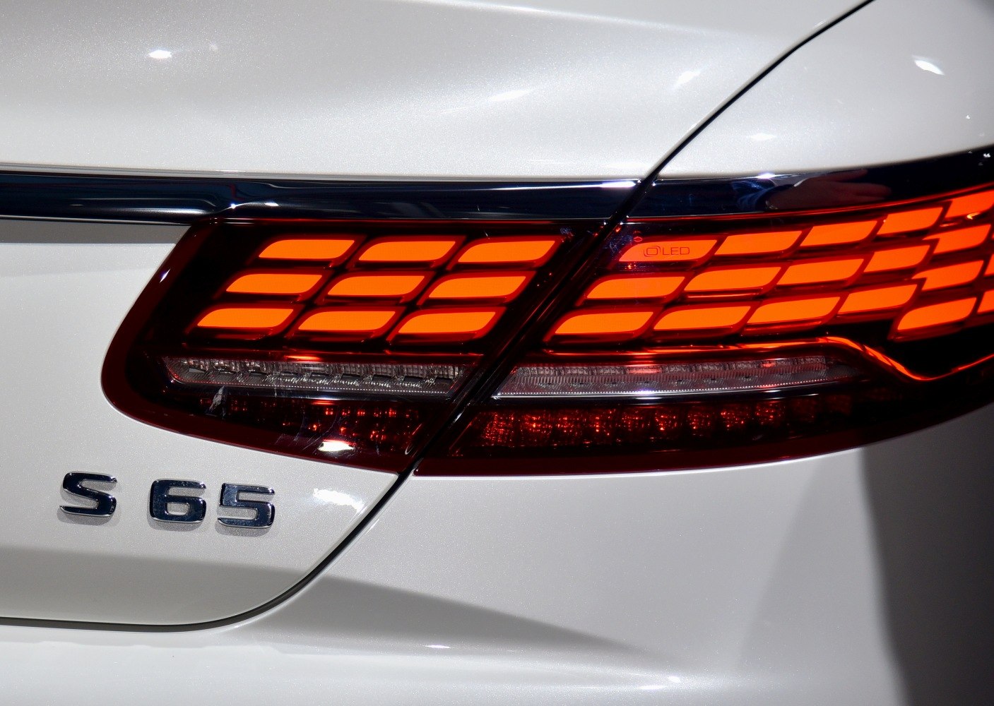 Rear LED tail light and S 65 badge on white luxury car