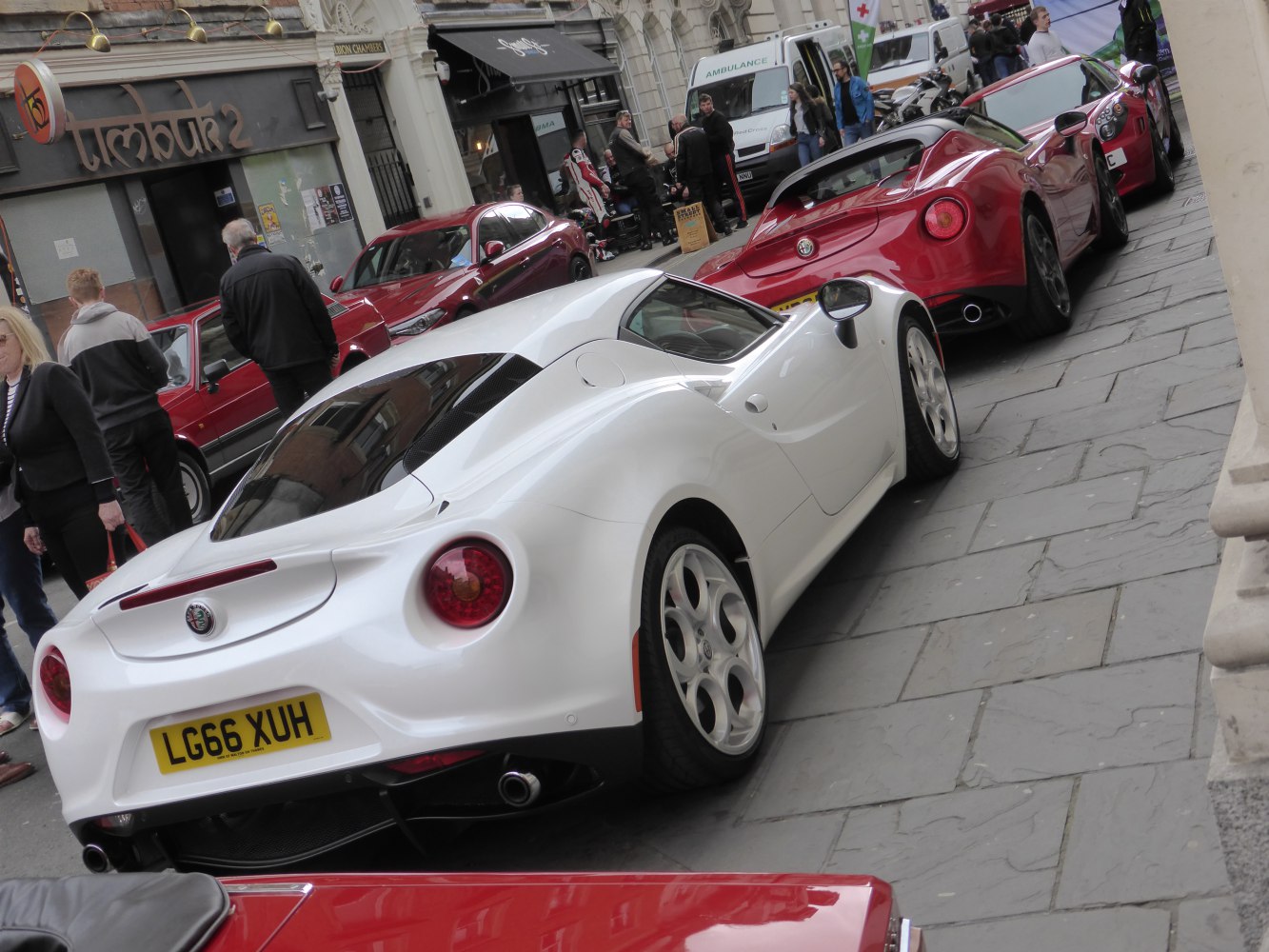 Rear and side views of white and red sporty coupes with round taillights and sleek design.