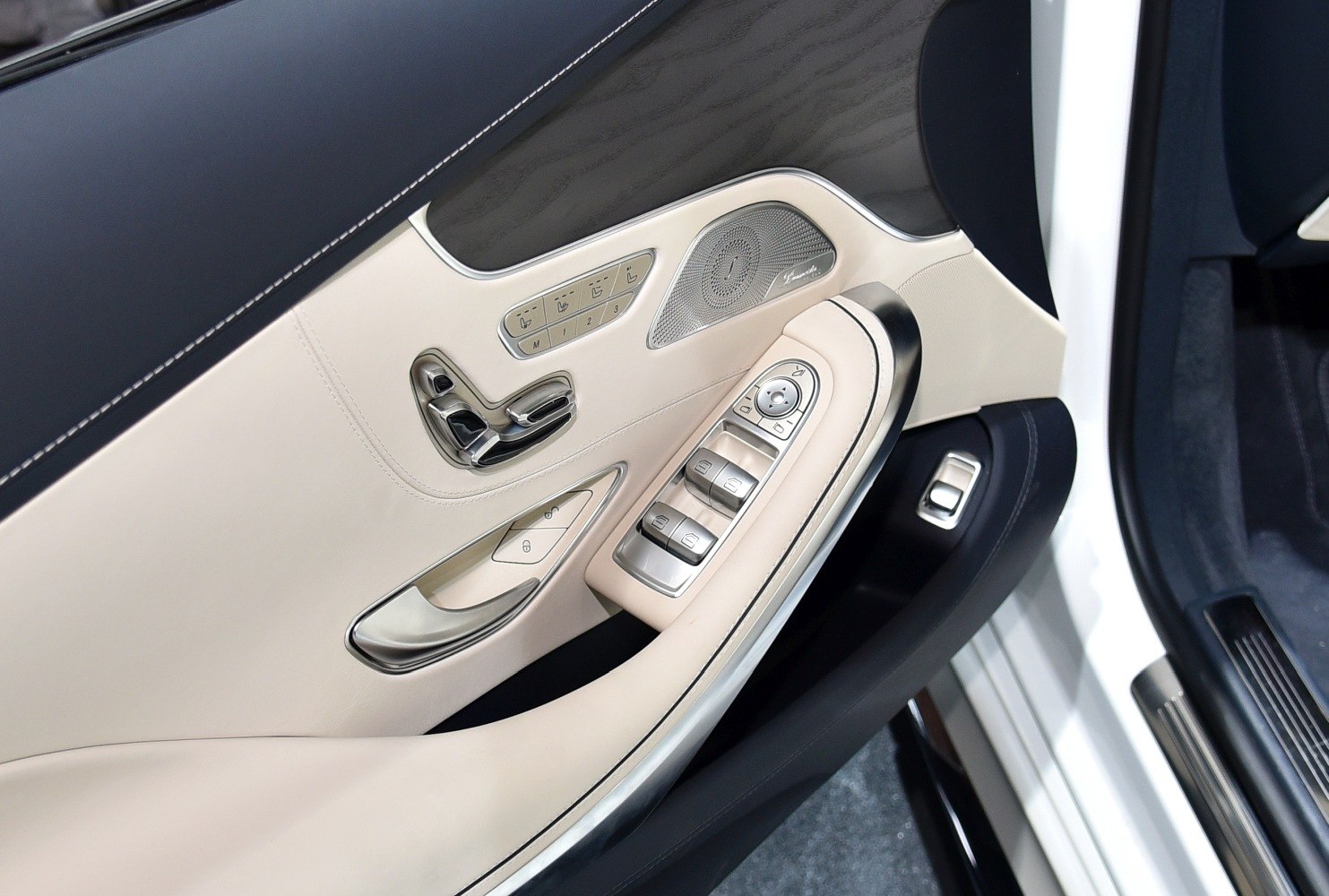 Beige leather door panel with chrome seat controls and Burmester speaker