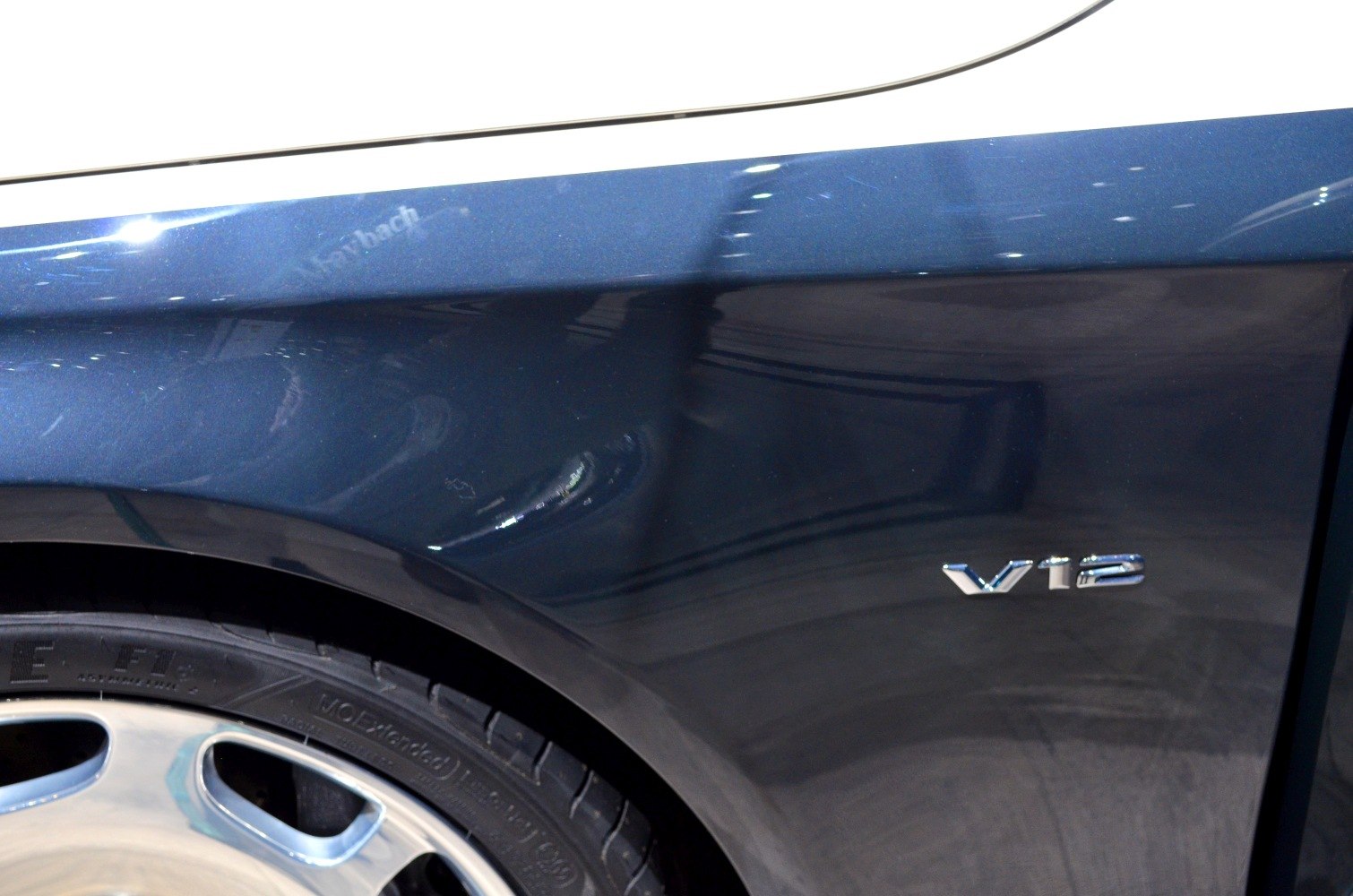 Close-up of V12 emblem and alloy wheel on dark blue vehicle body