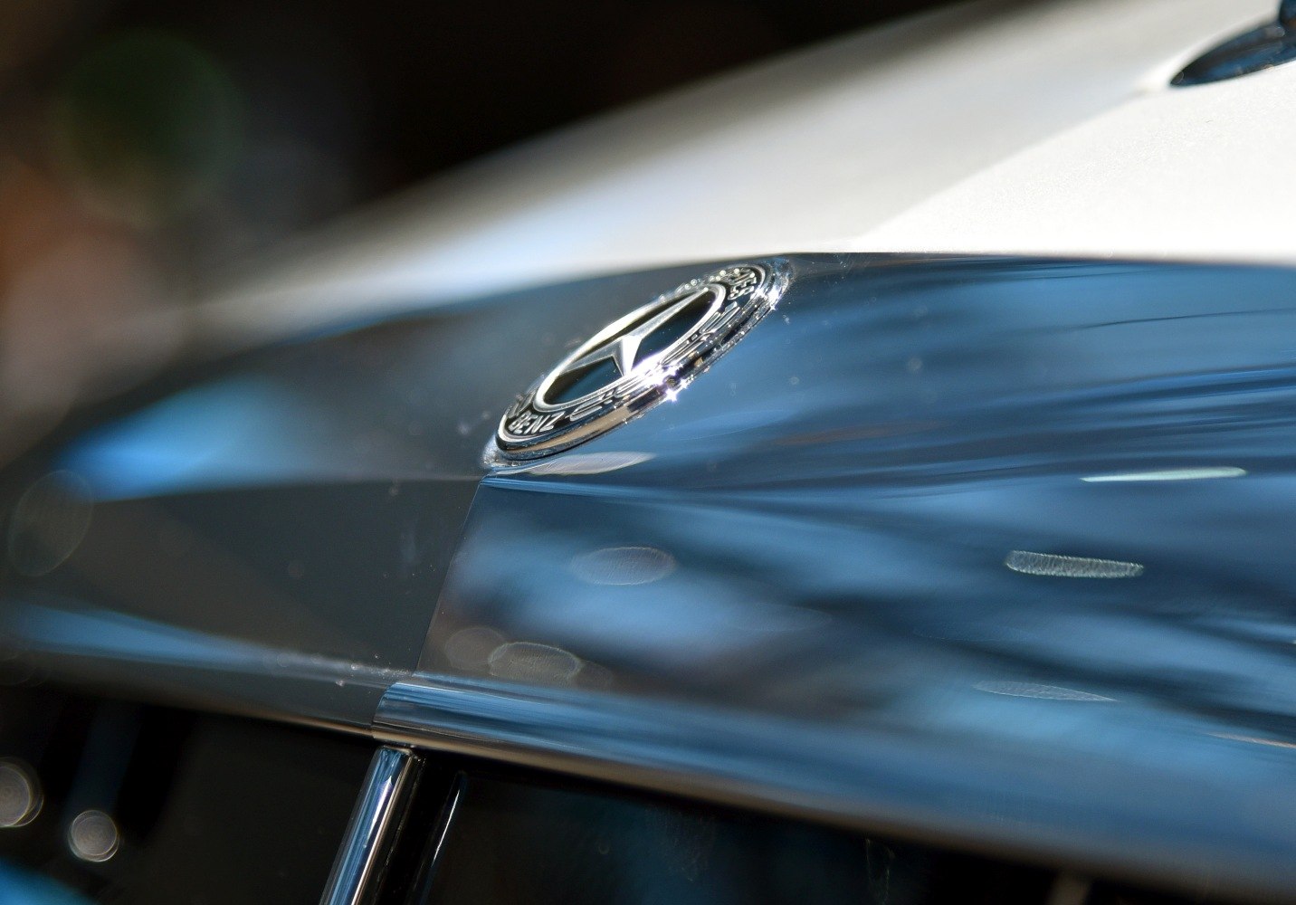 Close-up of chrome luxury car hood emblem and front grill detail