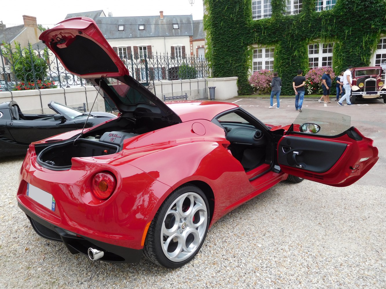 Open rear engine compartment and driver door on red sports coupe