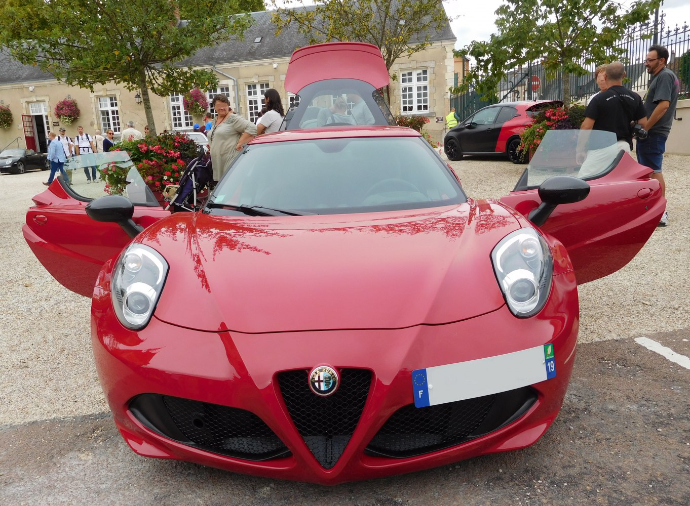 Red sports coupe with open doors and rear hatch