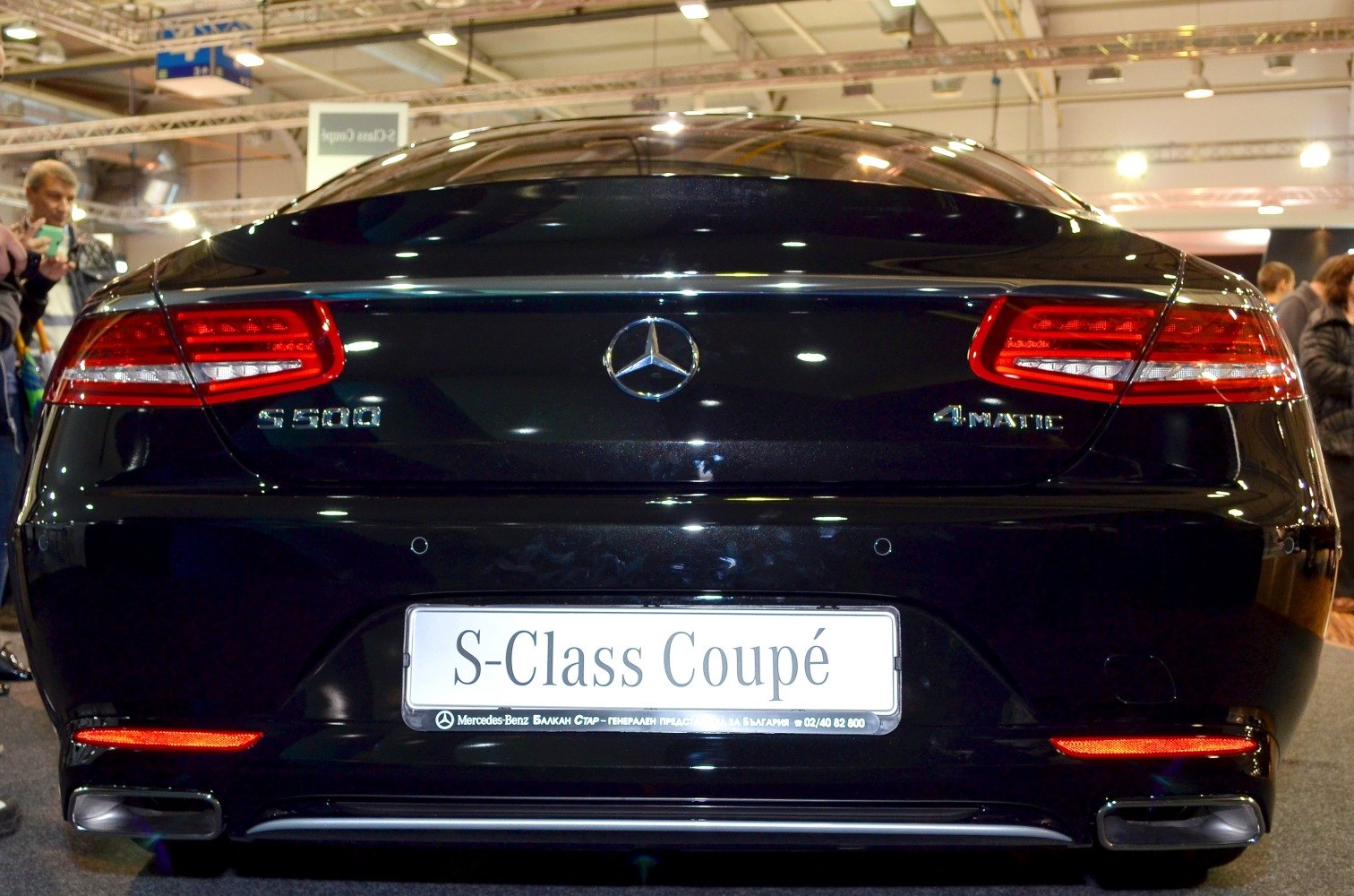 Rear view of black luxury coupe with LED tail lights and dual exhaust