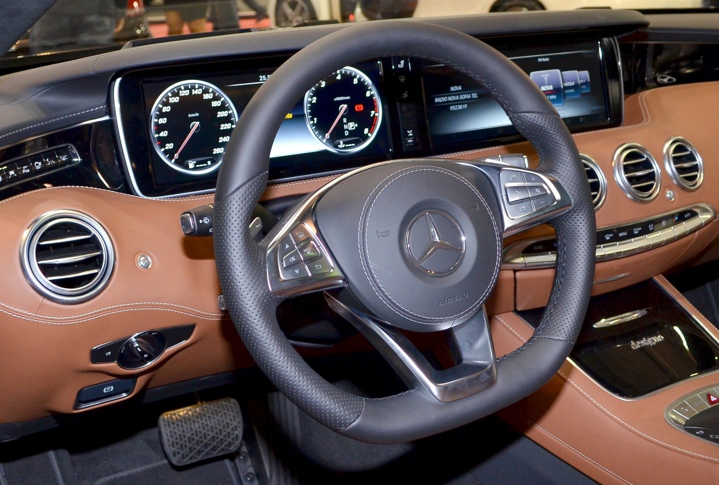 Luxury steering wheel with digital instrument cluster and brown leather dashboard.