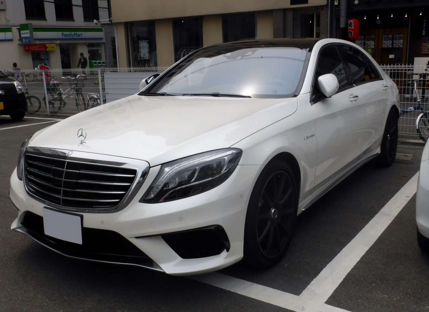 Luxury white sedan with black wheels and LED headlights in parking spot.