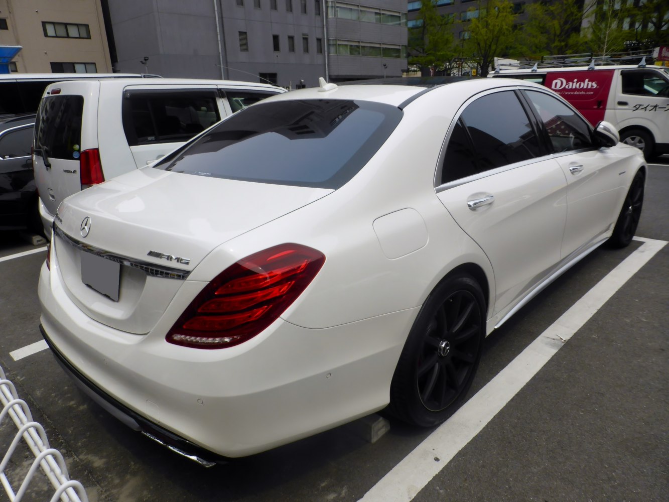 Rear and side view of white luxury sedan with black wheels and tinted windows