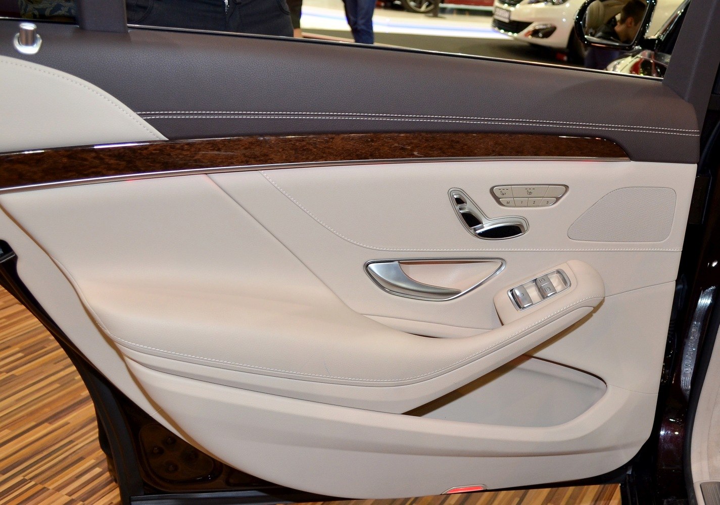 Luxury car door panel with leather, wood trim, and seat control buttons
