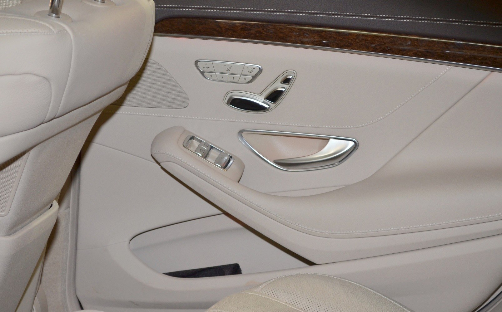 Beige car door panel with seat adjustment buttons, window controls, and wood trim