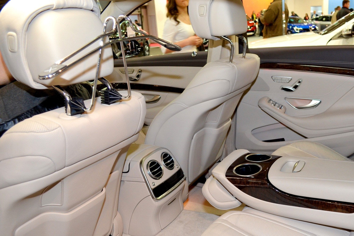 Rear passenger area with leather seats, coat hanger, wood trim, cup holders, and air vents