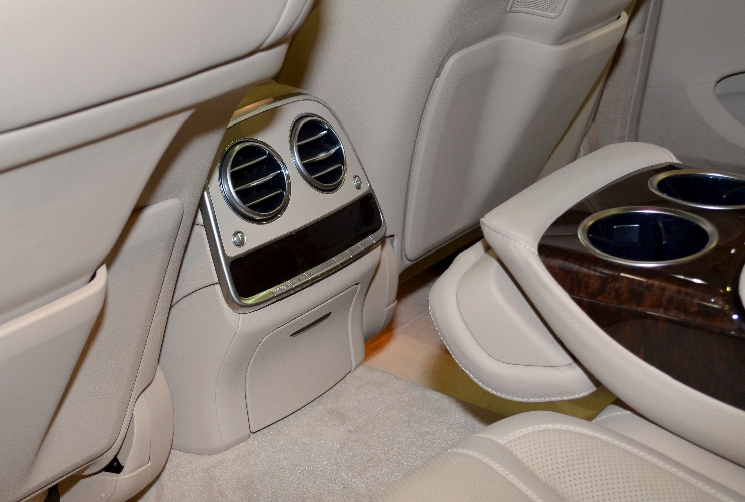 Rear air conditioning vents and wooden trim cupholder in beige interior