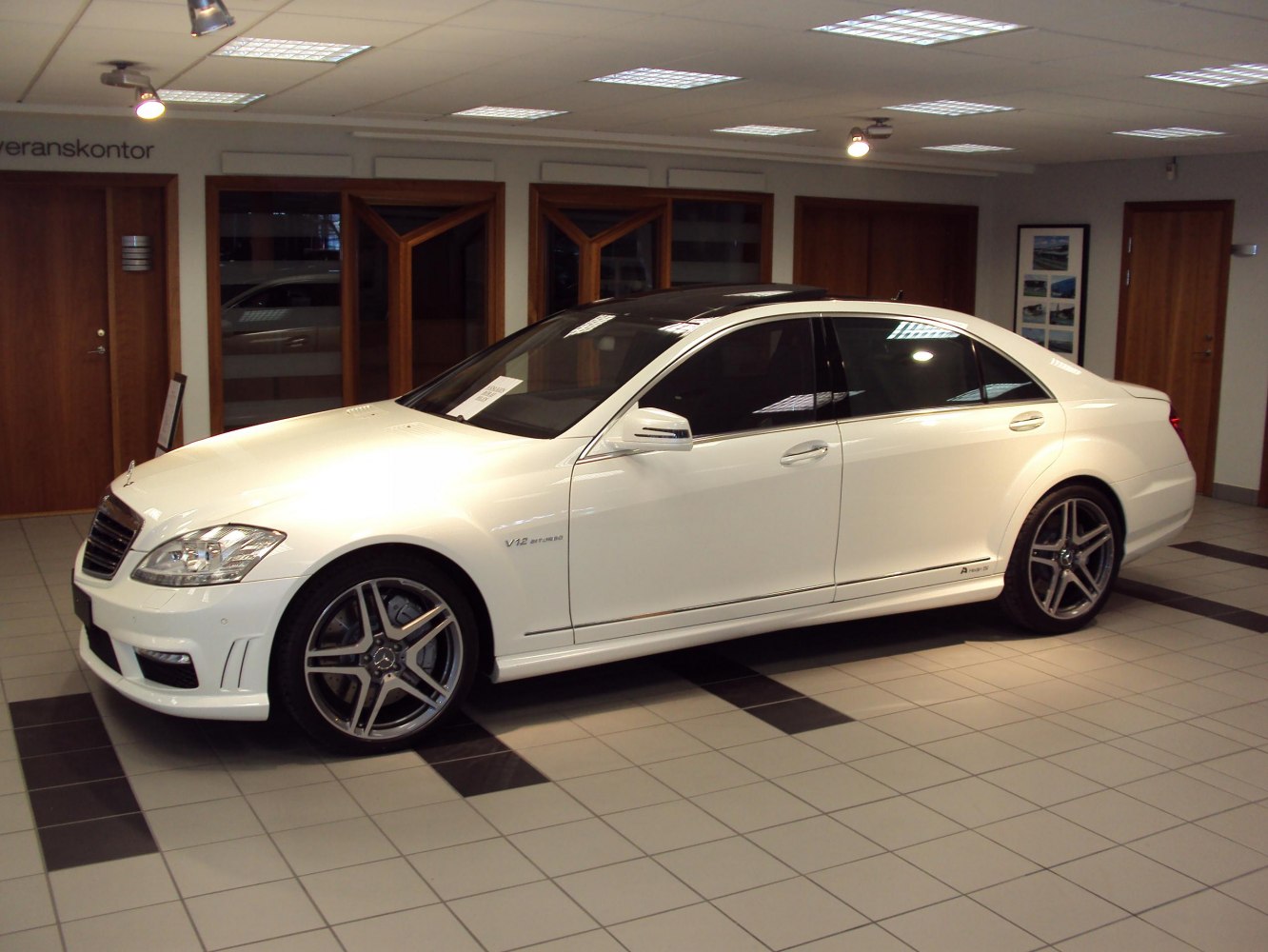 White luxury sedan with AMG wheels and V12 engine badge