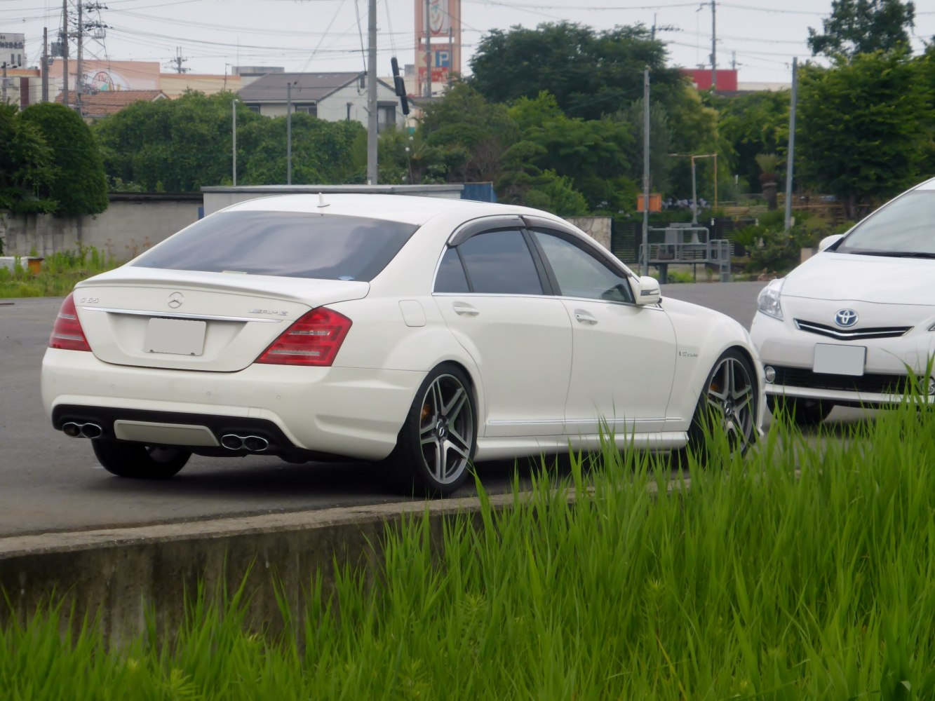 White luxury sedan rear with quad exhaust and AMG wheels