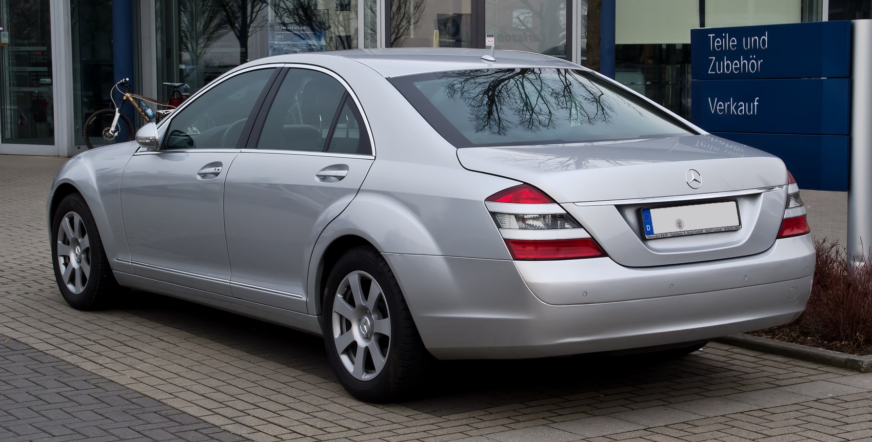 Silver luxury sedan rear side with distinctive taillights and chrome trim