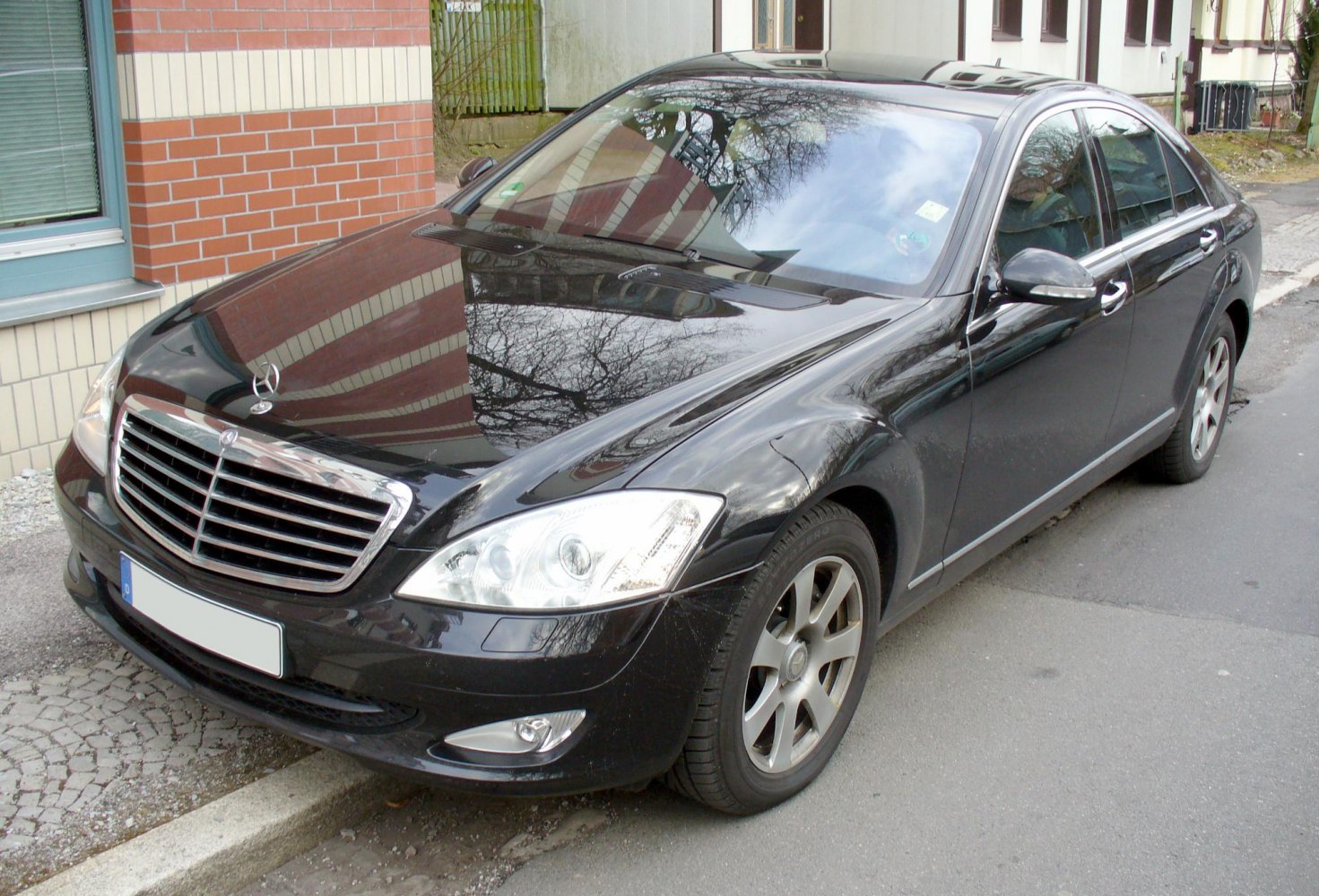Black luxury sedan with chrome grille and sharp headlights in urban parking