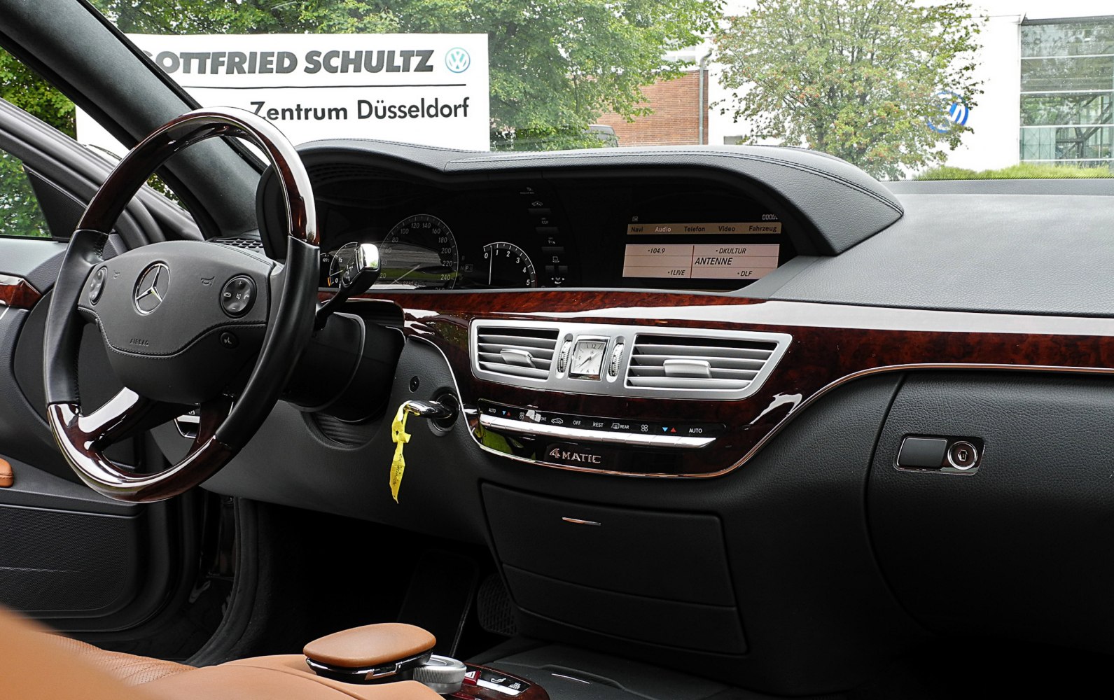 Luxury dashboard with wood trim, analog clock, leather steering wheel, and digital display.