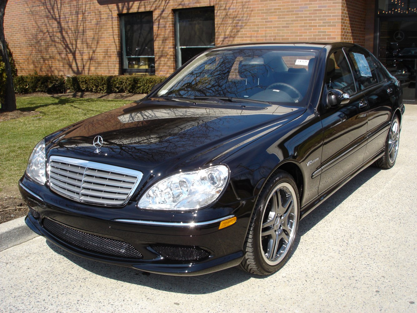 Luxury black sedan with chrome grille and V12 badge