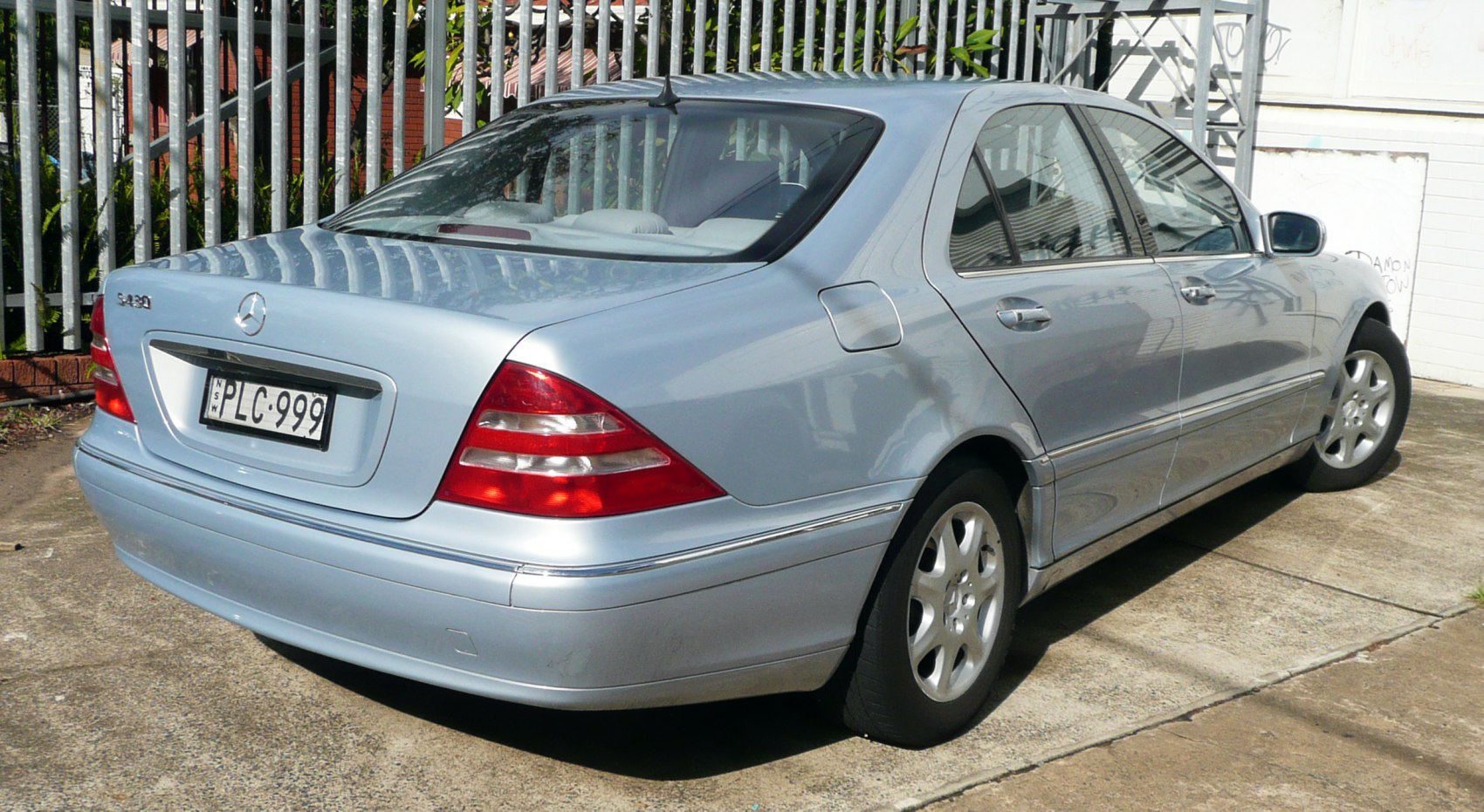 Rear and side view of blue luxury sedan with distinctive taillights.