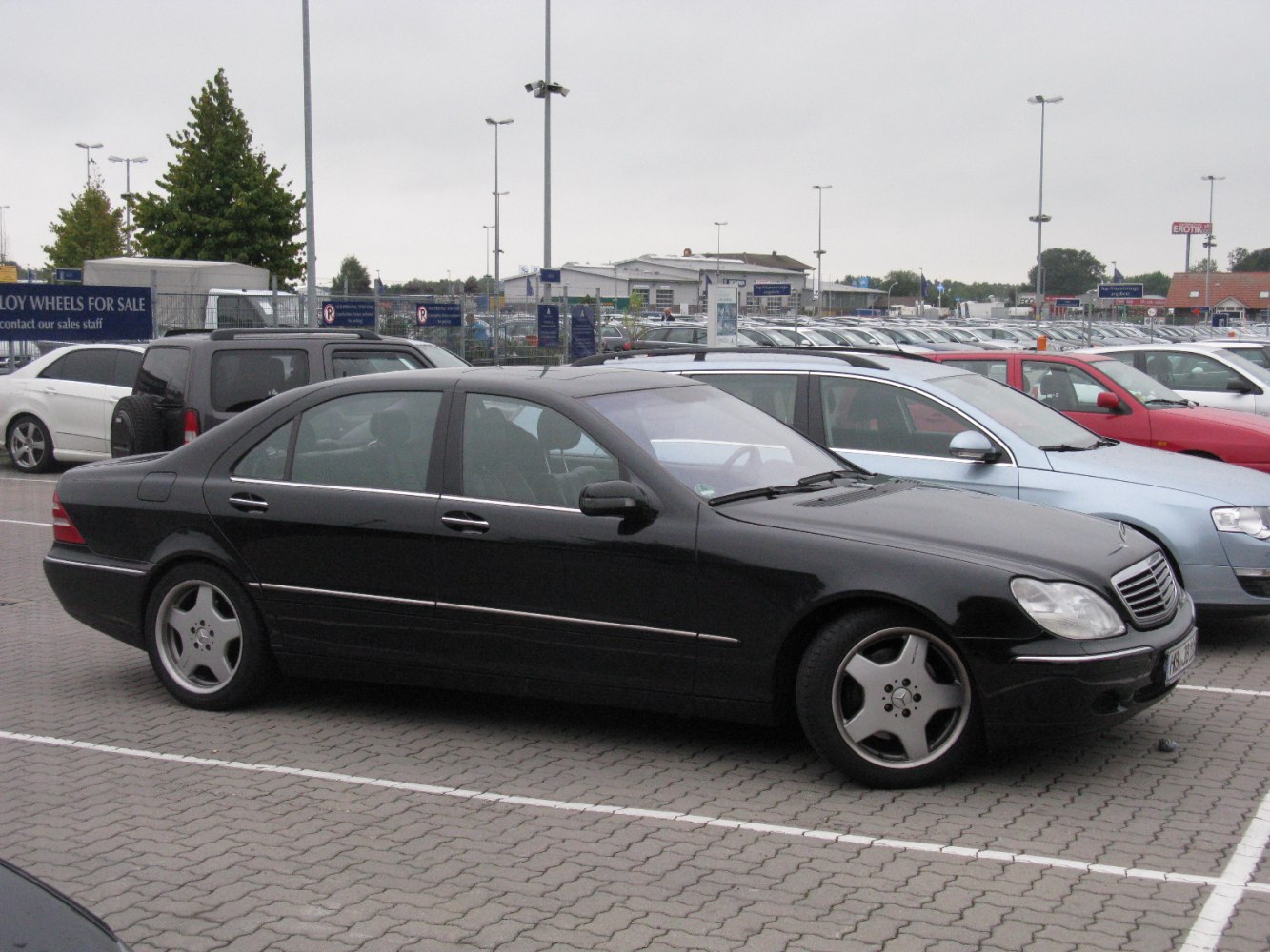 Black elongated sedan with five-spoke wheels parked in lot