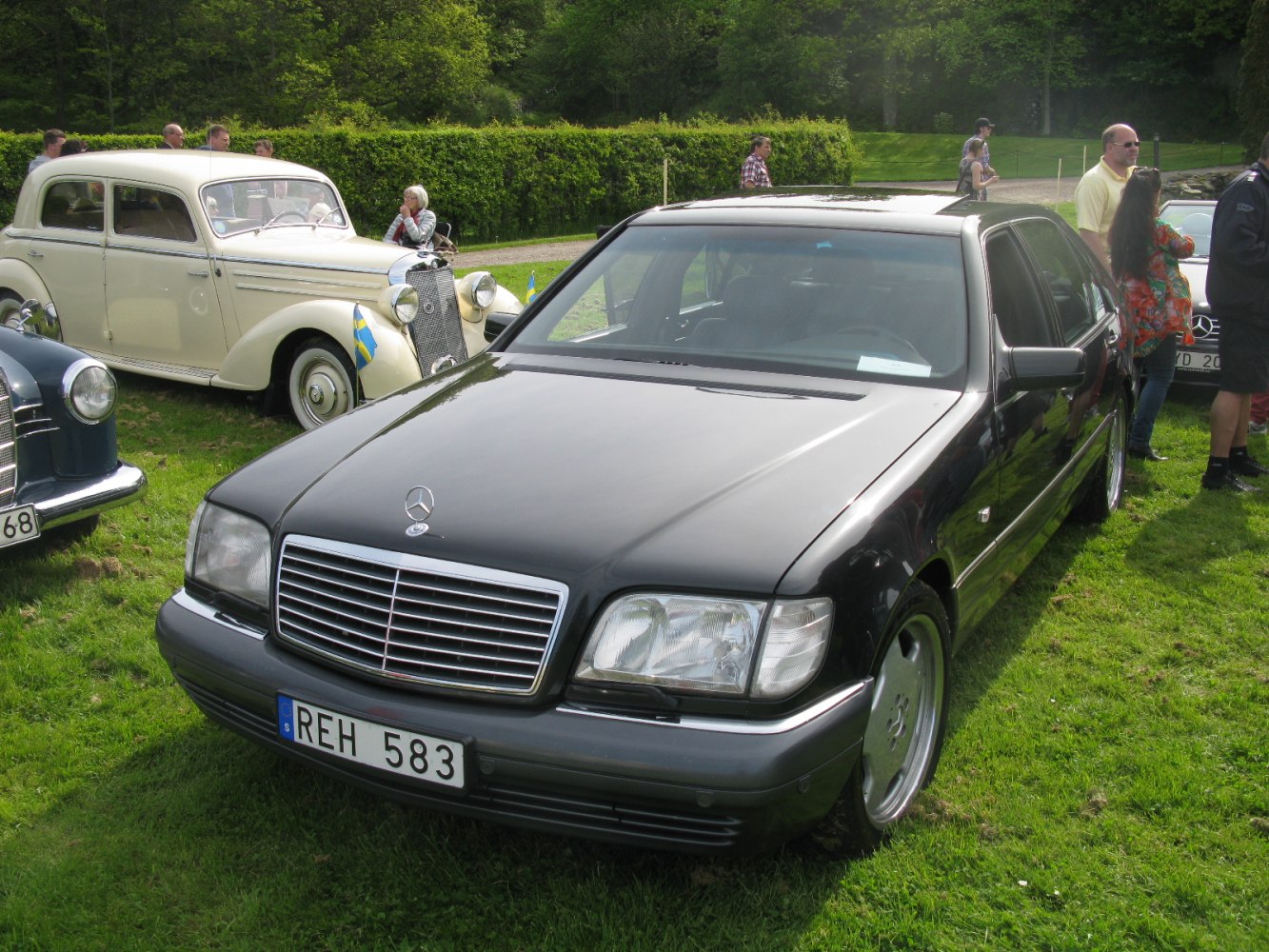 Black luxury sedan with chrome grille and emblem in front view.