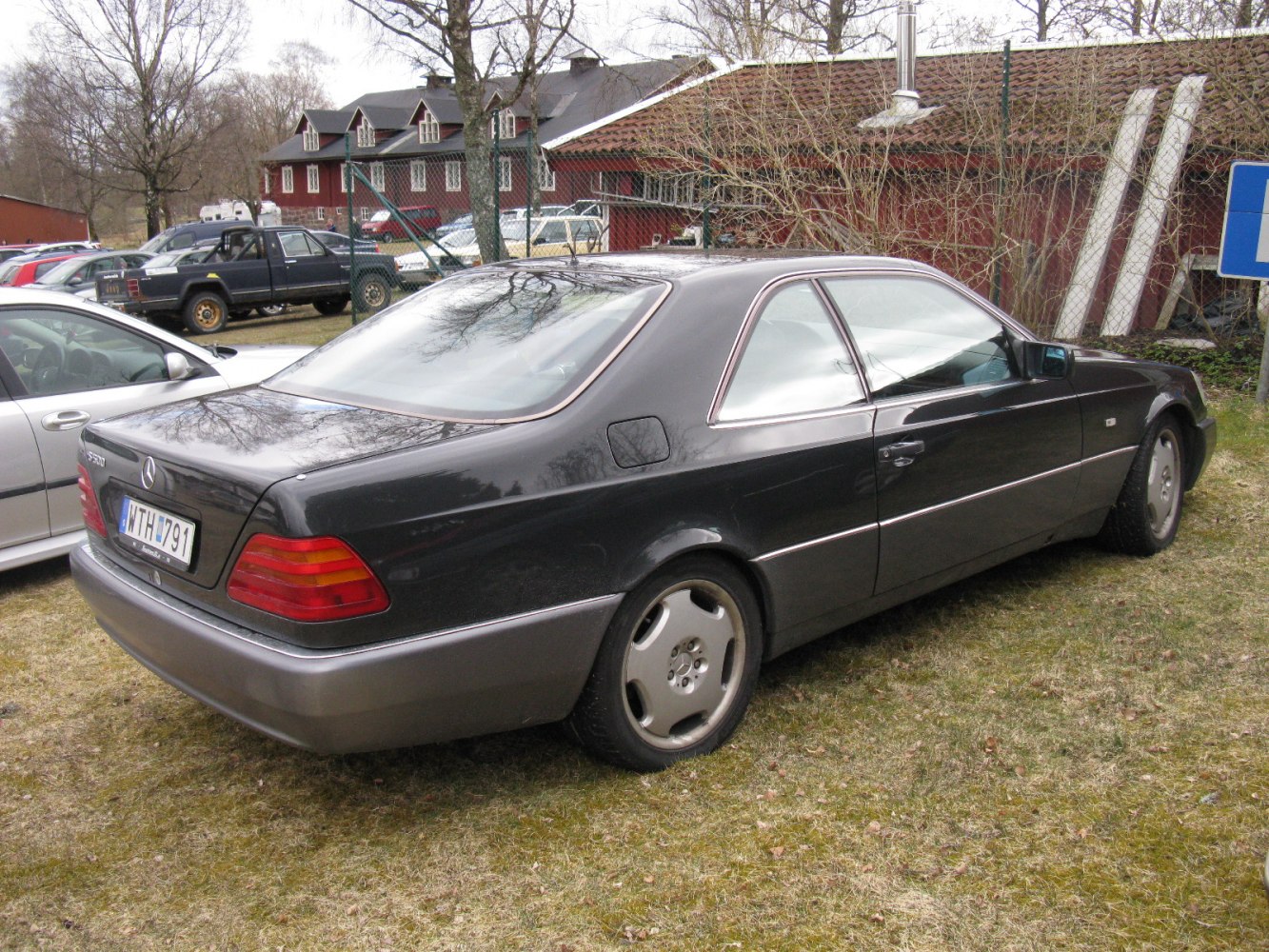 Rear and side view of a 1990s luxury coupe with alloy wheels and classic taillights