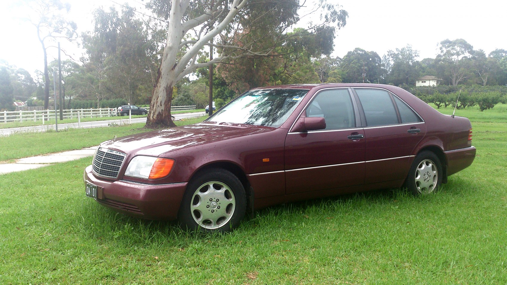 Side view of classic 1990s sedan with boxy shape and alloy wheels.