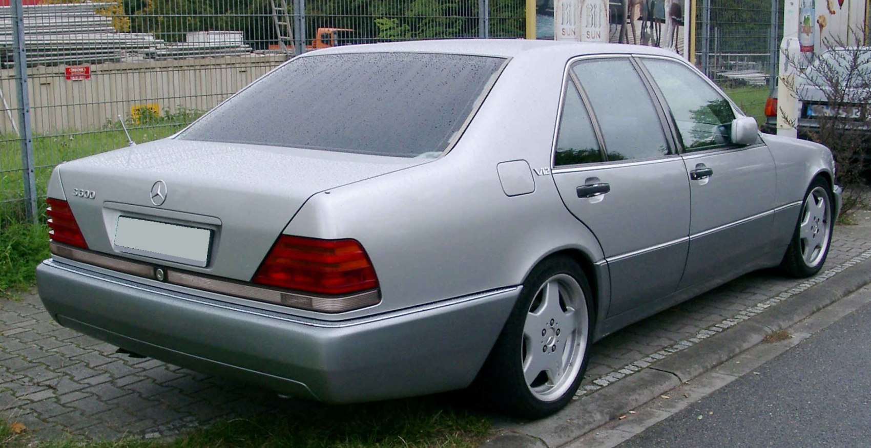 Rear side view of sedan with V12 badge and distinct tail lights