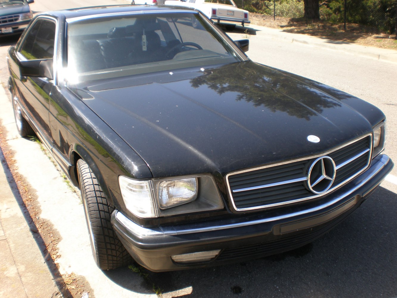 Front angled view of black luxury coupe with rectangular headlights and iconic grille