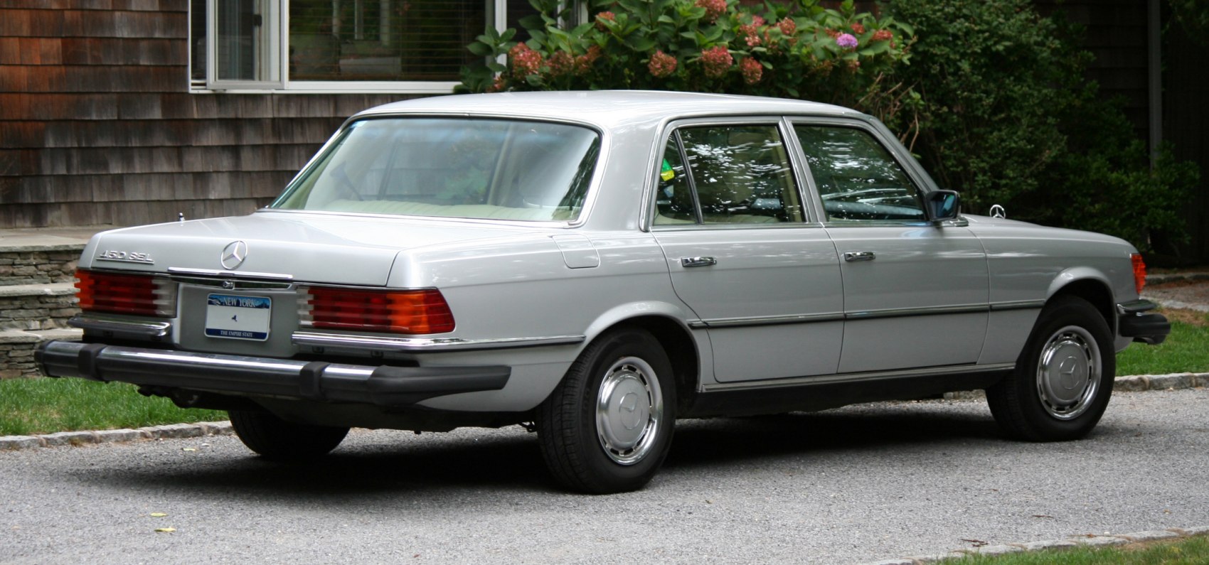 Rear and side view of vintage luxury sedan with chrome bumper and large tail lamps
