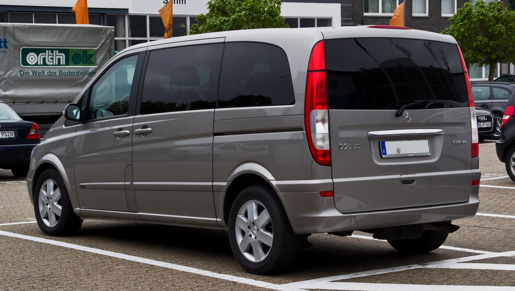 Rear and side view of a silver multi-purpose van with tinted windows and vertical tail lights