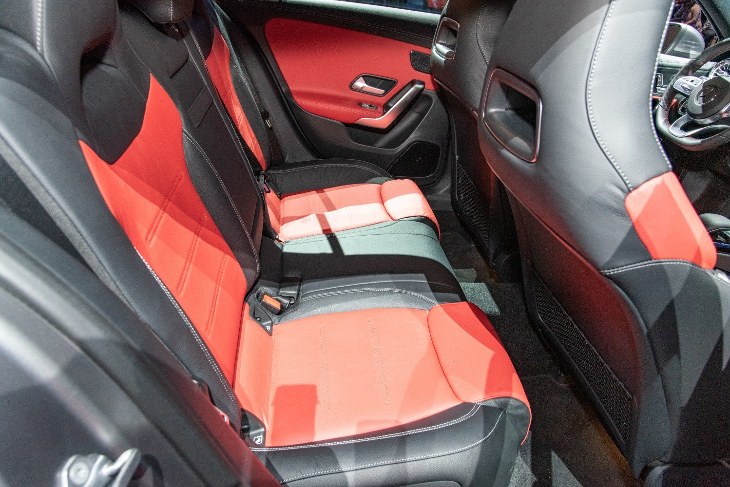 Red and black leather rear seats in compact vehicle interior
