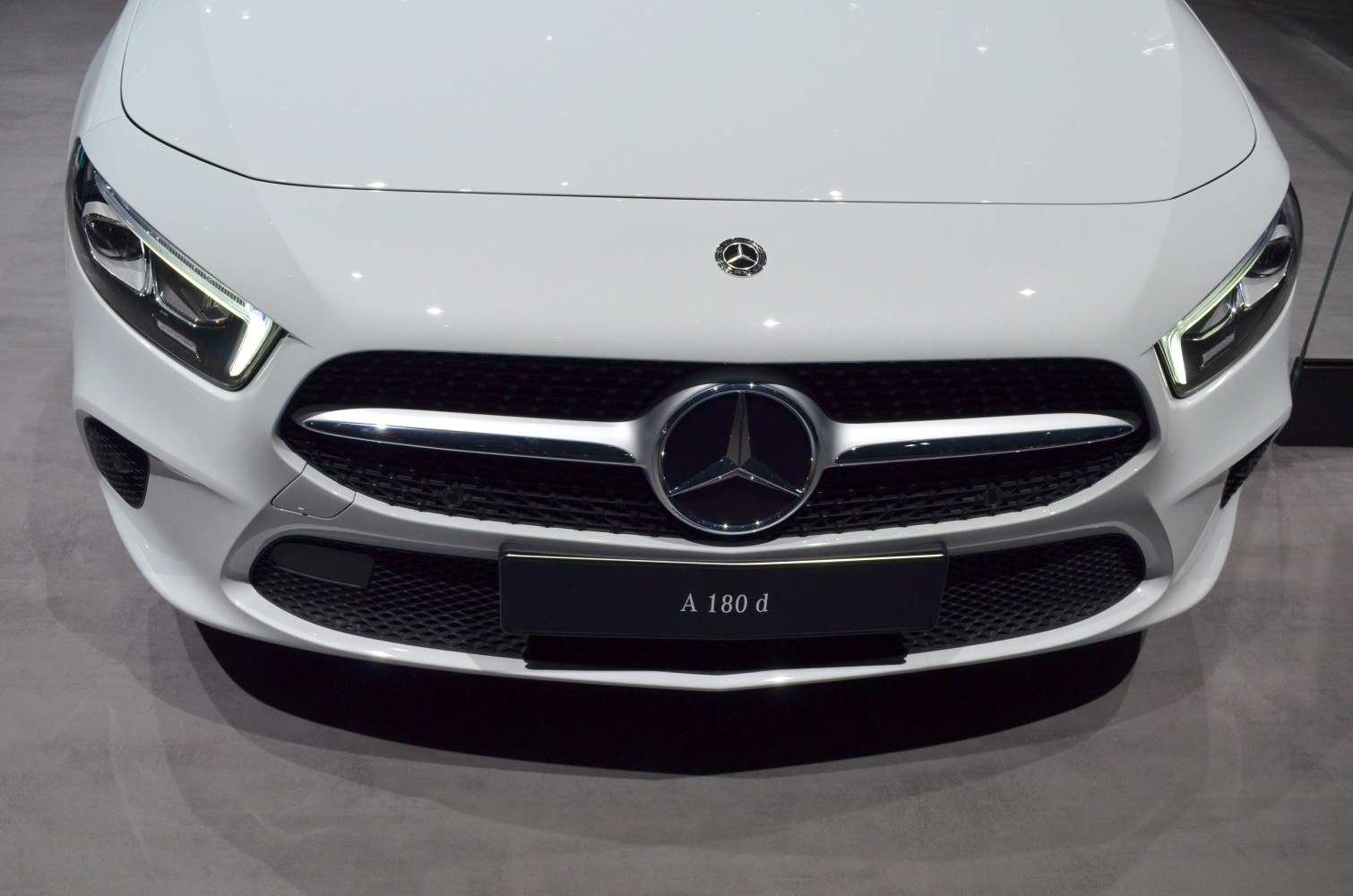 Front grille and LED headlights of a white luxury compact car