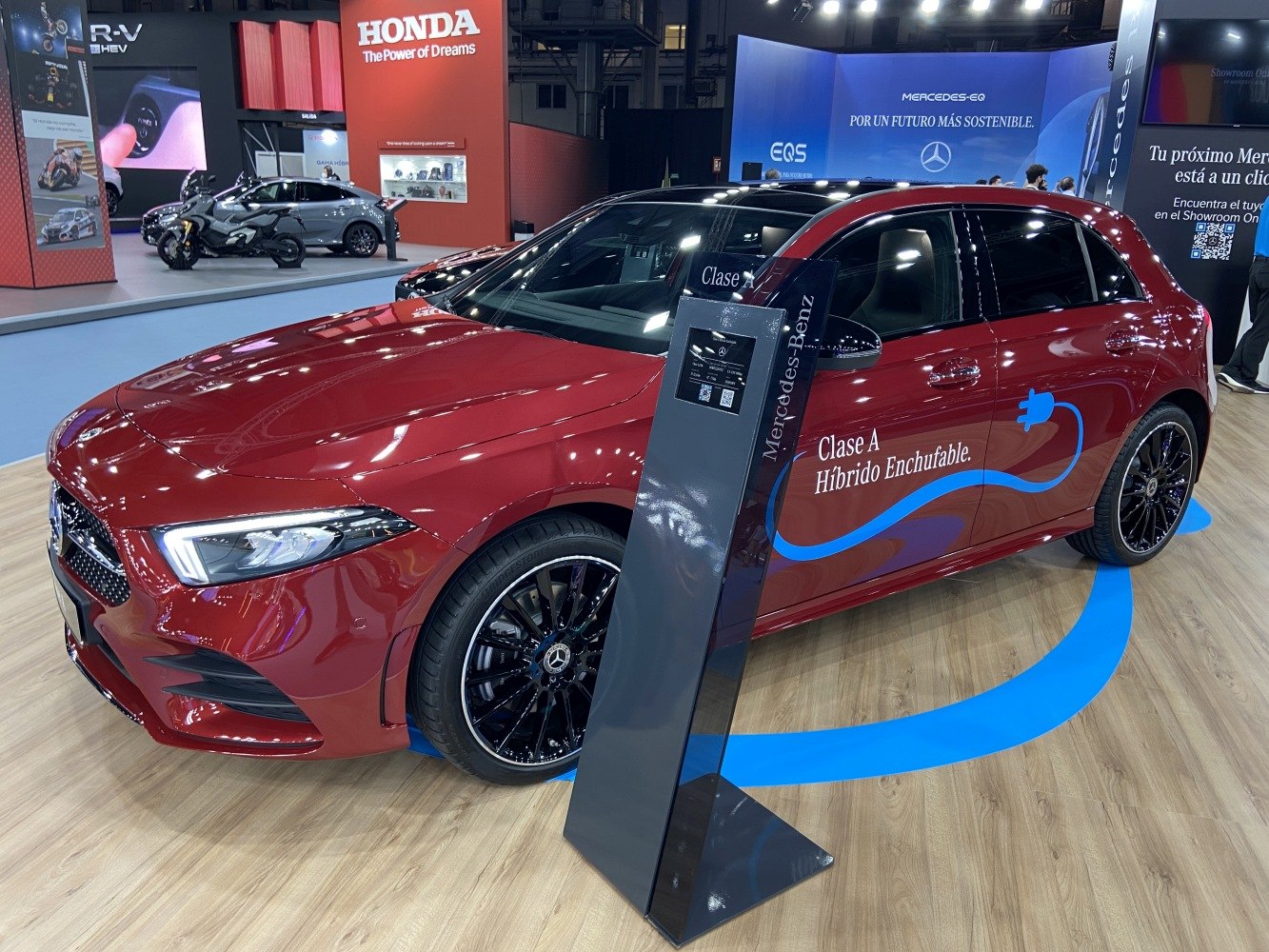 Red plug-in hybrid hatchback with black rims and electric charging decal.