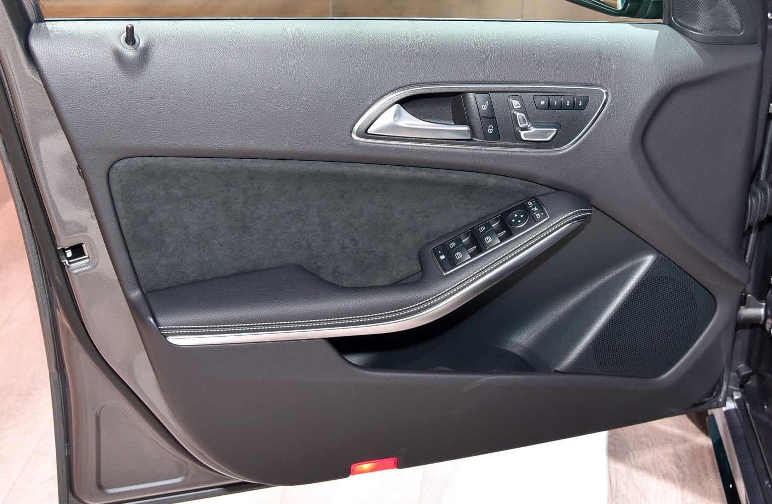 Car door panel with controls, handle, and textured trim