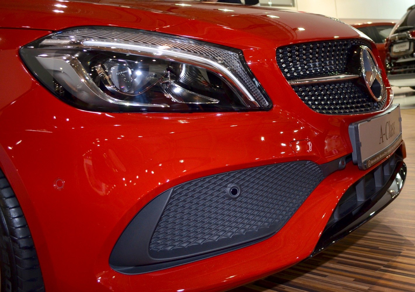 Front headlight and grille with parking sensor on a compact luxury hatchback.
