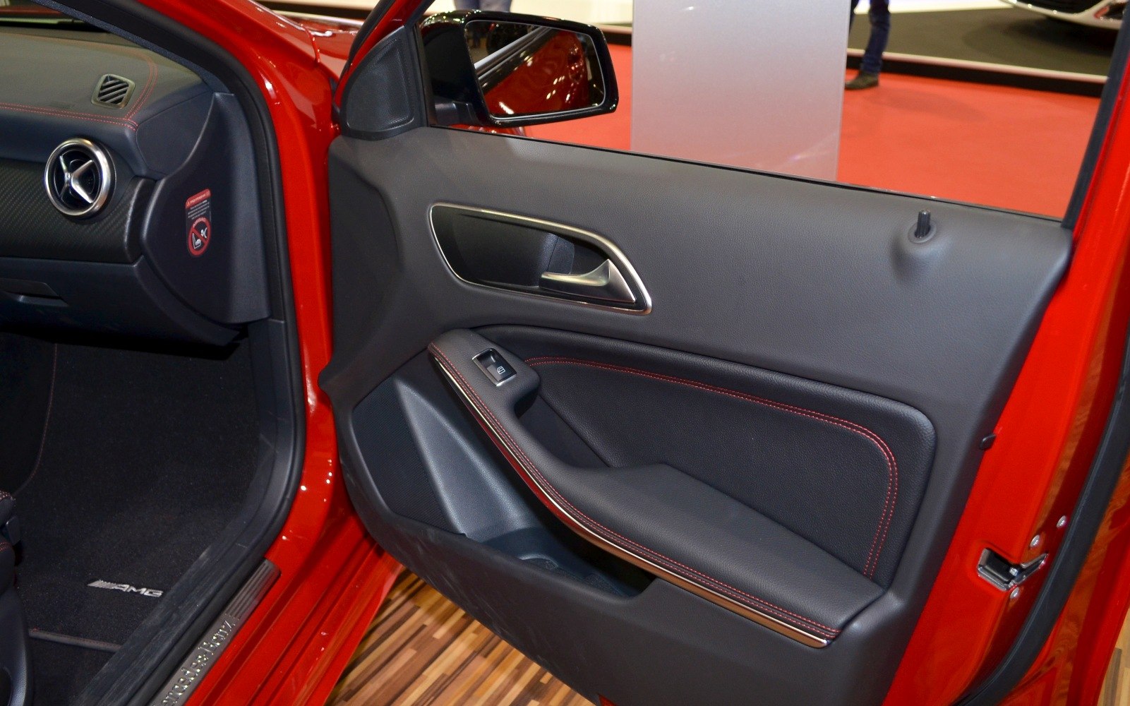 Car door interior with black leather, red stitching, and chrome handle trim