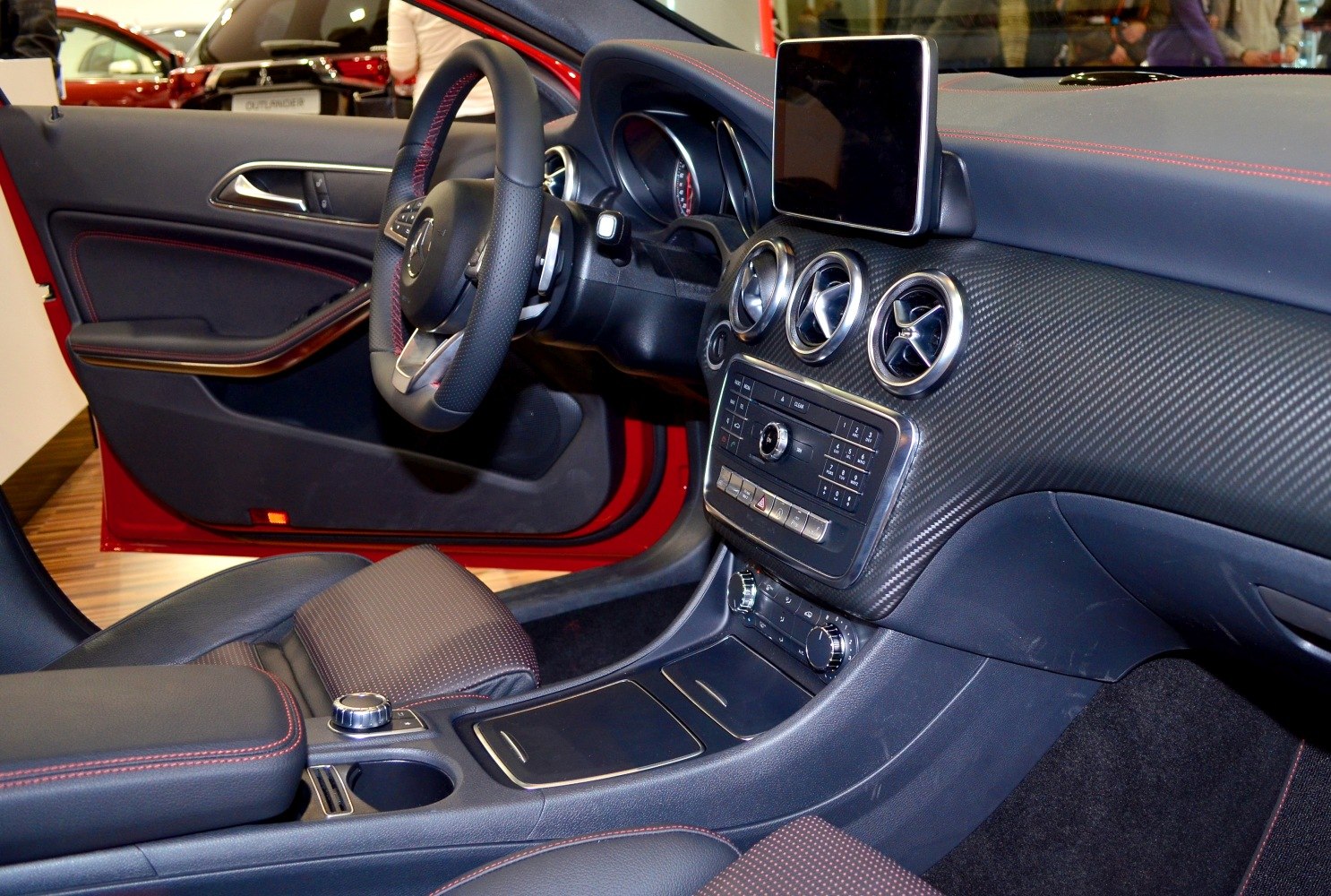 Modern dashboard with carbon fiber, round vents, infotainment screen, and steering wheel