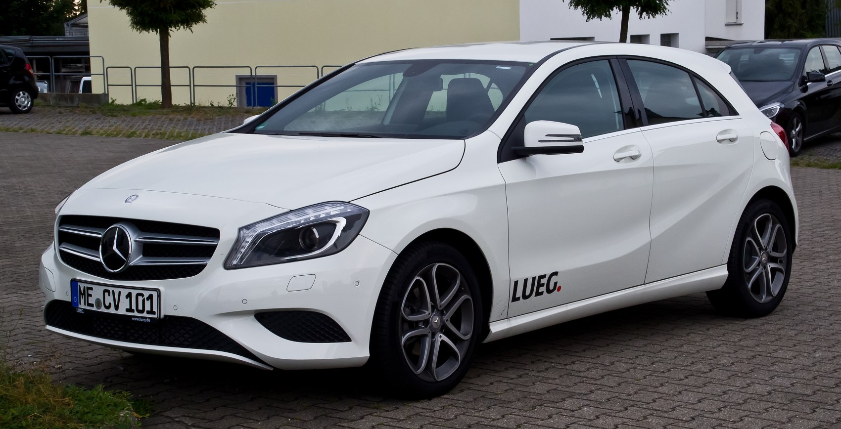Front side view of a white hatchback car with distinctive headlights and alloy wheels