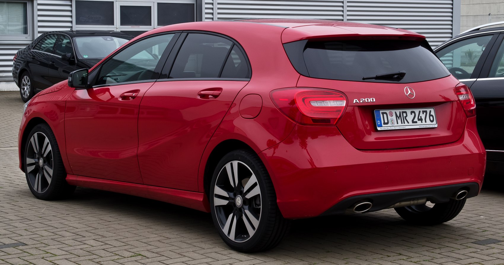 Rear side view of red hatchback with dual exhaust and alloy wheels