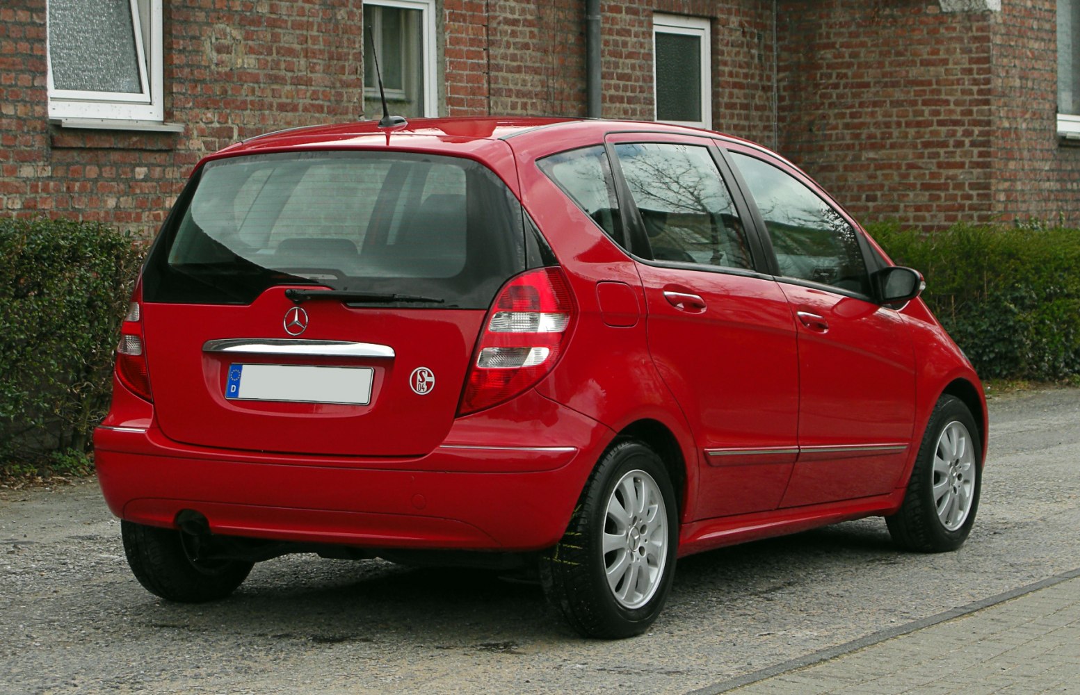 Red compact hatchback showing rear and side view with distinct taillights and rear wiper