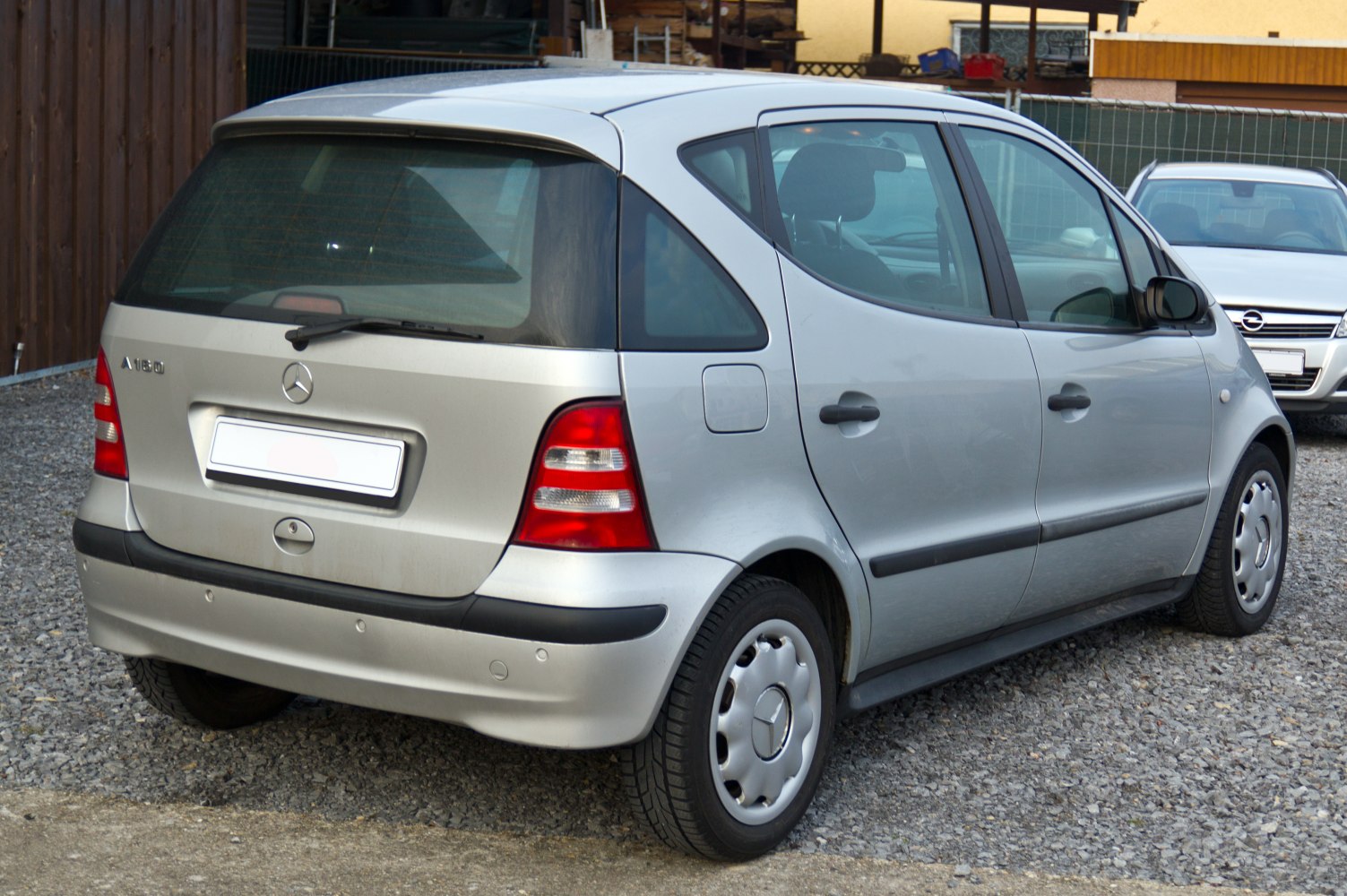 Rear side view of compact silver hatchback with distinctive taillights and black trim