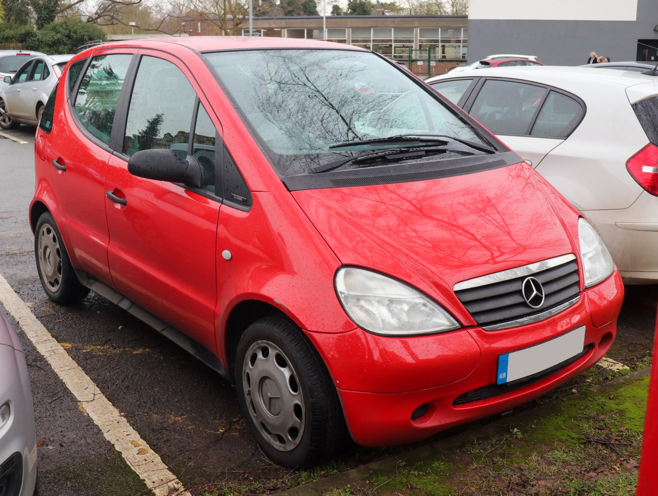 Compact red hatchback, rounded headlights, horizontal grille