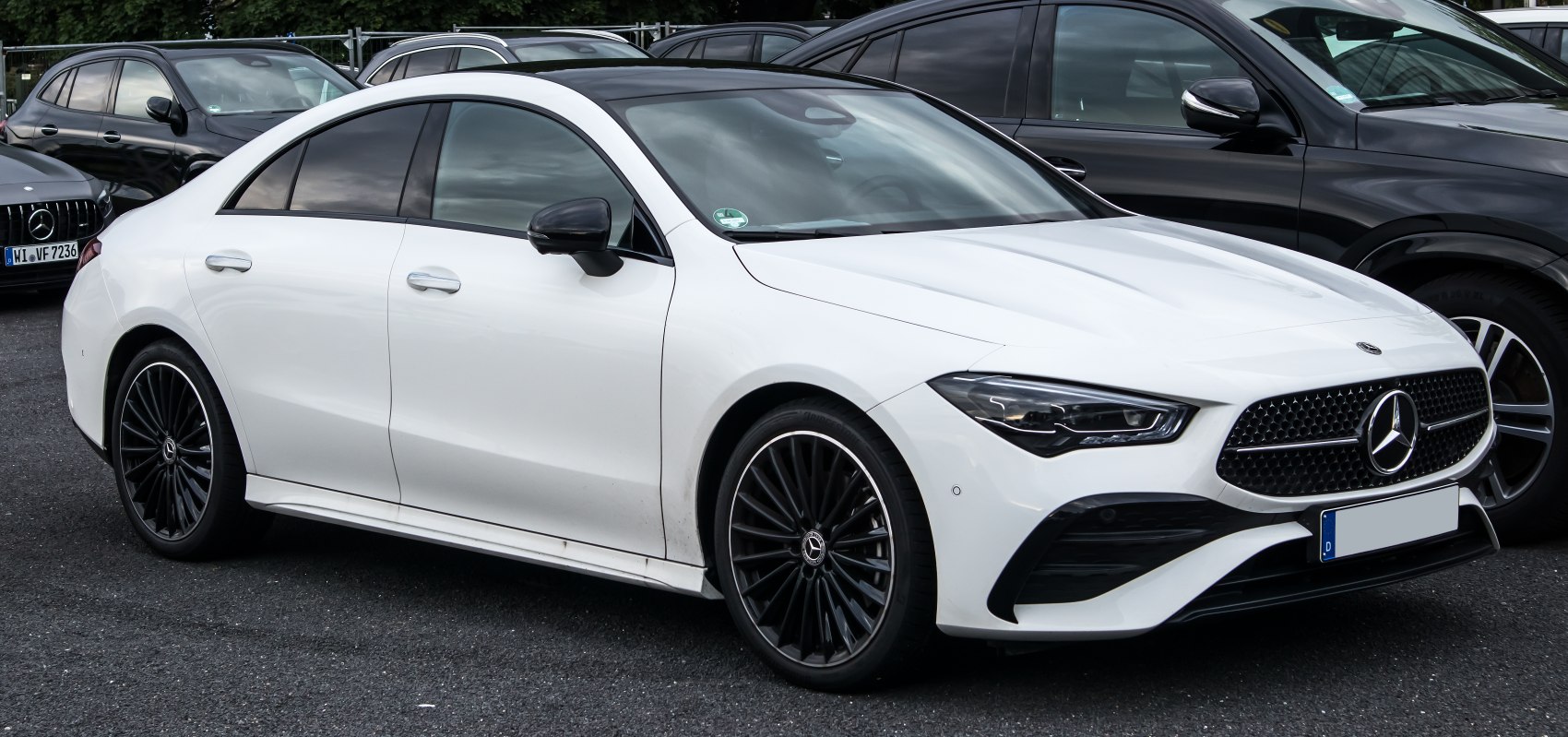 Glossy black multi-spoke alloy wheels and sharp angular LED headlights on a sleek coupe.
