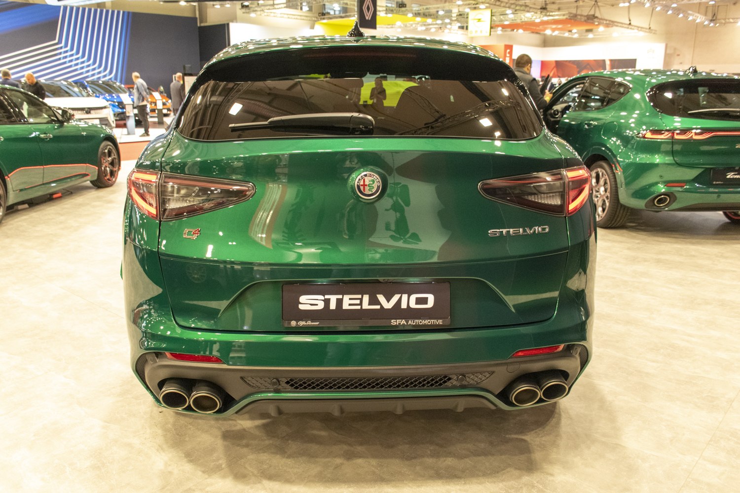 Rear view of deep green SUV with quad exhaust pipes and sleek tail lights.